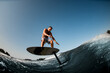 adult man ride down the wave with hydrofoil foilboard on background of blue sky