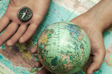 a globe and a compass in the hands of a person on the background of a geographical map of the world the concept of travel tourism