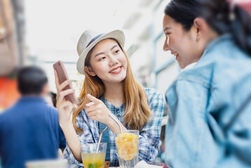 Wall Mural - Traveler Asian woman friend travel in Bangkok, Thailand, sweet couple taking photo . Lifestyle couple travel in city concept.Young fun happy Asian tourist backpacker travel eating street food.