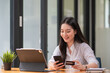 © Songsak C - Young woman holding credit card and using laptop computer. Online shopping concept.
