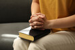 Religious woman praying over Bible indoors, closeup