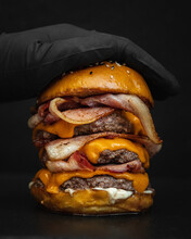 Close-up Shot Of A Giant Delicious Mouthwatering Burger With Fried Bacon, Melted Cheese, And Beef