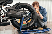 Young Man Cleaning Or Working With BMW Black Sportbike. Modern Powerful Motorcycle