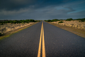 Converging lines country road with dunes and cloudy sky