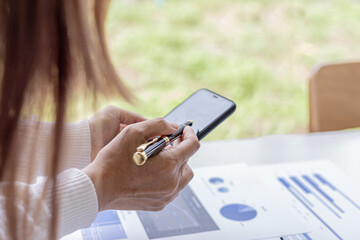 Poster - businesswoman holding a mobile phone, she is looking at information on mobile phone that the financial officer sends through an online messaging program. Financial concepts.