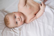 © Tina kids photo - a cute baby is lying in diapers in a bed with white cotton bed linen. High quality photo