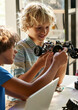 © insta_photos - School kids boys helping in building robotic car learning together at STEM class. Happy students children studying together playing making robots in classroom at science and coding education lesson.