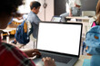 © insta_photos - African junior school kid girl student using laptop computer with white blank empty mockup screen at desk in classroom. Online education class software website tech ads concept. Over shoulder view