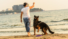 Female Dog Owner With His Long-haired German Shepherd Trains At Sea Beach