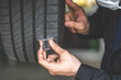 © NVB Stocker - Mechanic checking checking the depth of car tire tread.  Car maintenance and auto service garage concept.