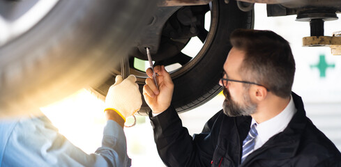 Sticker - Hipster manger with beard and checklist clipboard talk to Expertise mechanic working Under a Vehicle in a Car Service station. Car care and automobile service garage concept.