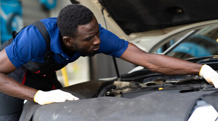 Sticker - Black male mechanic repairs car in  garage. Car maintenance and auto service garage concept.