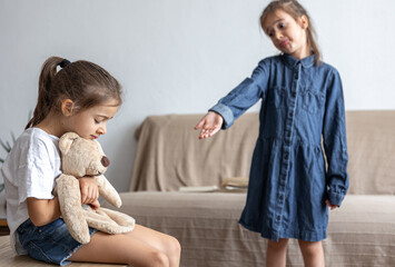 Wall Mural - Sisters quarrel over a toy, they cannot share a teddy bear.