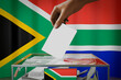 © PX Media - South Africa flag, hand dropping ballot card into a box - voting, election concept - 3D illustration