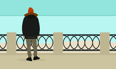 Wall Mural - A male character in a jacket and a hat stands on the embankment and looks at the sea