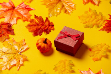 Wall Mural - Romantic gift box with autumn leaves on yellow background. Top view