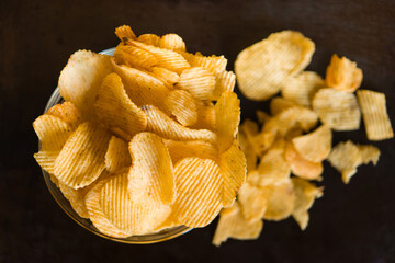 Wall Mural - Crispy potato chips in a plate on metallic black grunge background