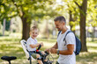 © Dusan Petkovic - Getting ready for the bike ride. Father and son bonding time in nature. A cute boy is sitting in a bicycle basket while his father prepping his basket bells for the bonding time. Smiling together