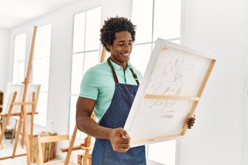 Poster - Young african american artist man smiling happy holding canvas at art studio.