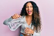© Krakenimages.com - Young latin woman pouring water smiling and laughing hard out loud because funny crazy joke.