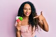 © Krakenimages.com - Young latin woman holding ice cream smiling happy pointing with hand and finger