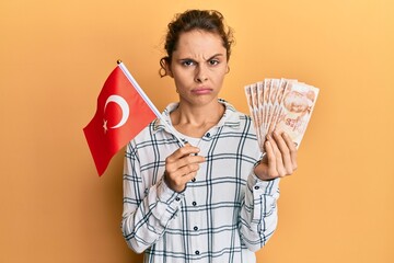 Sticker - Young brunette woman holding turkey flag and liras banknotes skeptic and nervous, frowning upset because of problem. negative person.