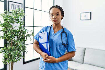 Canvas Print - Young african american woman working wearing doctor uniform working at the clinic thinking attitude and sober expression looking self confident