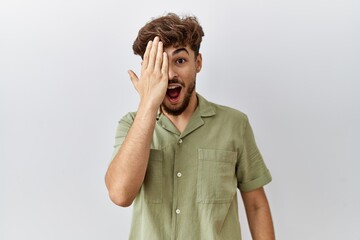 Wall Mural - Young arab doctor man standing over isolated background covering one eye with hand, confident smile on face and surprise emotion.