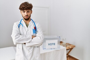 Poster - Young arab doctor man at political election by ballot skeptic and nervous, disapproving expression on face with crossed arms. negative person.