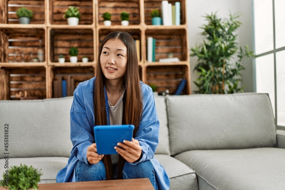 Young chinese girl using touchpad sitting on the sofa at home. Stock ...