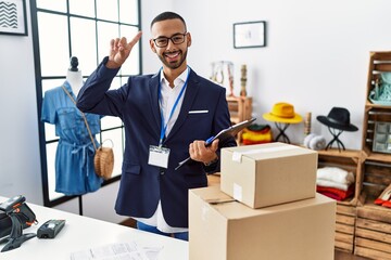 Poster - African american man working as manager at retail boutique smiling amazed and surprised and pointing up with fingers and raised arms.