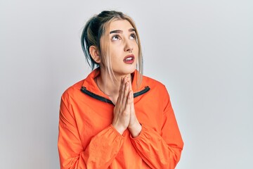 Wall Mural - Young modern girl wearing sports sweatshirt begging and praying with hands together with hope expression on face very emotional and worried. begging.