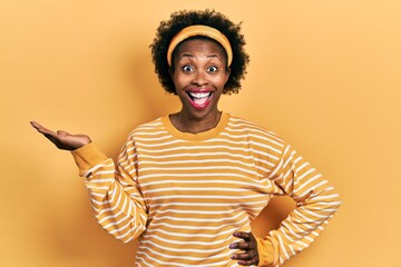 Canvas Print - Young african american woman presenting with open palms, holding something celebrating crazy and amazed for success with open eyes screaming excited.