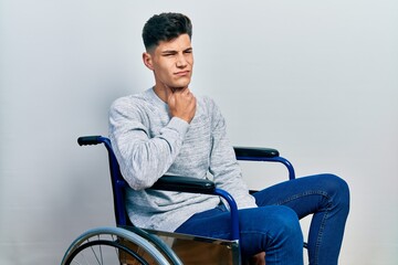 Wall Mural - Young hispanic man sitting on wheelchair touching painful neck, sore throat for flu, clod and infection