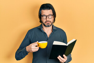 Poster - Middle age caucasian man reading book drinking cup of tea depressed and worry for distress, crying angry and afraid. sad expression.