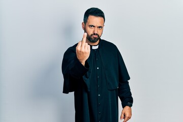 Poster - Handsome hispanic man with beard wearing catholic priest robe showing middle finger, impolite and rude fuck off expression