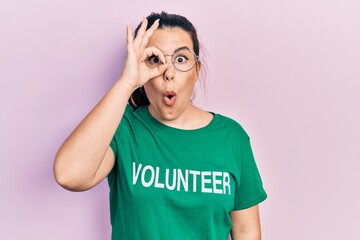 Sticker - Young hispanic woman wearing volunteer t shirt doing ok gesture shocked with surprised face, eye looking through fingers. unbelieving expression.