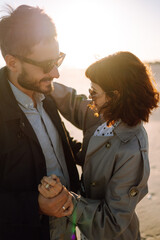 Wall Mural - Young couple having fun walking and hugging on beach during autumn sunny day. Relaxation, youth, love,  lifestyle solitude with nature.