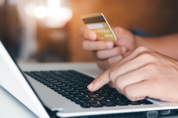 Businessman hand holding credit card with using laptop for online shopping while making orders at home. business, lifestyle, technology, ecommerce, digital banking and online payment concept.