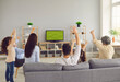 © Studio Romantic - Multi generational family watching football on television. View from behind three generations sitting on sofa enjoying World Cup soccer match on LED LCD plasma TV screen in modern living room interior