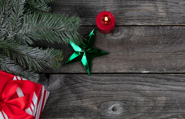 Wall Mural - Single bright green star ornament and burning candle, gift box plus snow fir branch decorations on rustic wooden planks for a merry Christmas or happy New Year holiday celebration concept