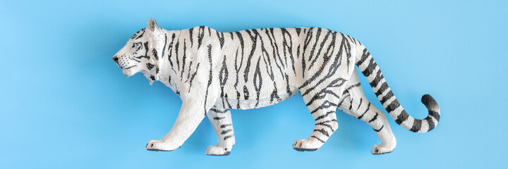 the tiger, symbol of 2022 year. plastic white toy figure tiger on a blue background. top view