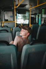 A Girl With Short Hair, In A Baseball Cap, In A Dress, Is Riding Alone On A Bus, A Beautiful Girl With Short Hair, Wearing A Hat On The Bus Smiles