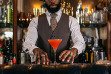 Anonymous Stylish Black Bartender With Red Martini Cocktail In Bar
