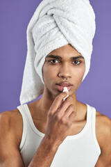 Wall Mural - Transgender young man use lips balm and looking camera portrait. African american model in towel