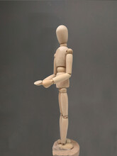 Wooden Human Body Figure Posing In Profile, In A Philosophical Position On An Intense Acid Gray Background. Wooden Model Concept For Learning To Draw Manga / Anime, Human Anatomy.