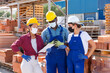 © JackF - Two builders and taskmaster in face mask talking while standing in outdoor construction material storage. They're checking documentation and planning work.