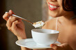 © DragonImages - Close-up image of smiling young woman enjoying delicious granola with yogurt