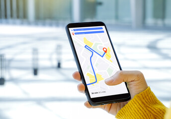 A woman in a yellow dress opens a travel map application on her mobile phone. travel concept and public car services.