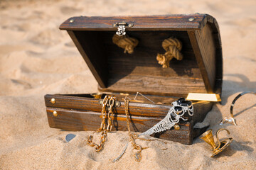 Open wooden chest with treasures on sand